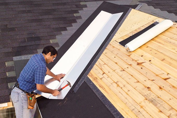 A man can be seen installing valley flashing on a roof