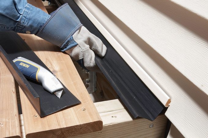 Hands can be seen installing z flashing for deck ledger boards
