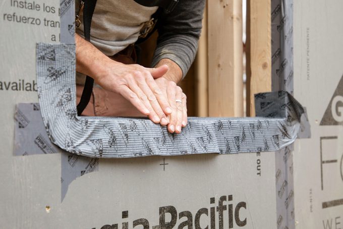 Hands can be seen installing drip cap flashing on window edge