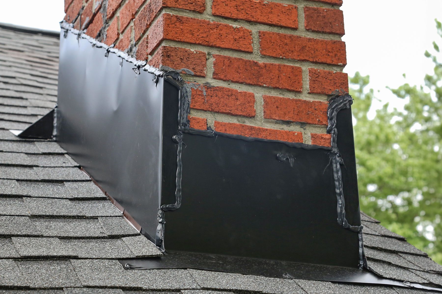 Flashing under a chimney on a roof.