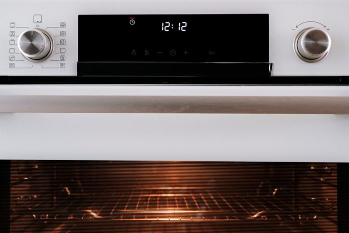 Buttons and control panel of a modern oven with the clock timer flashing.