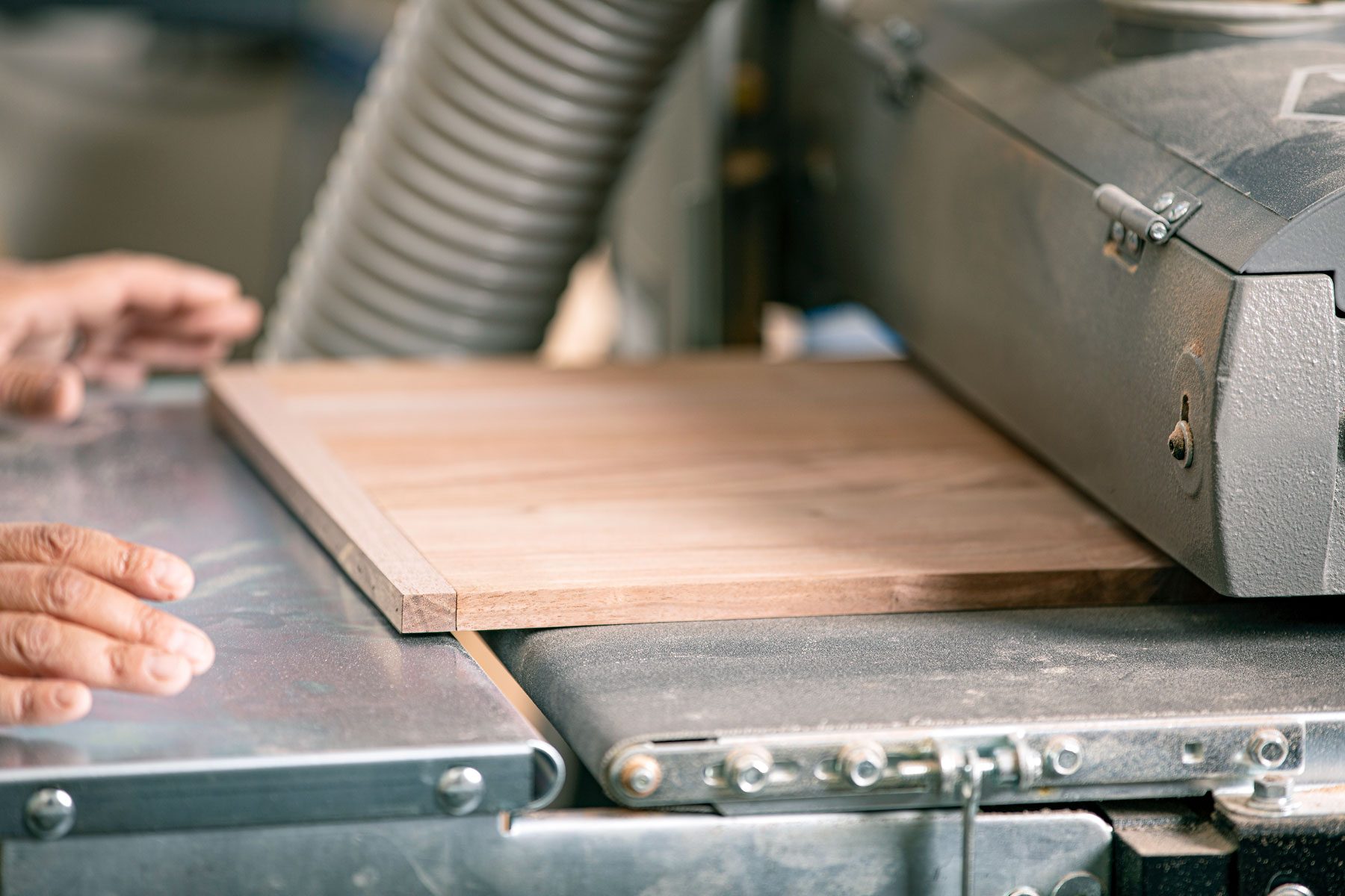 wooden panel being ran through sander