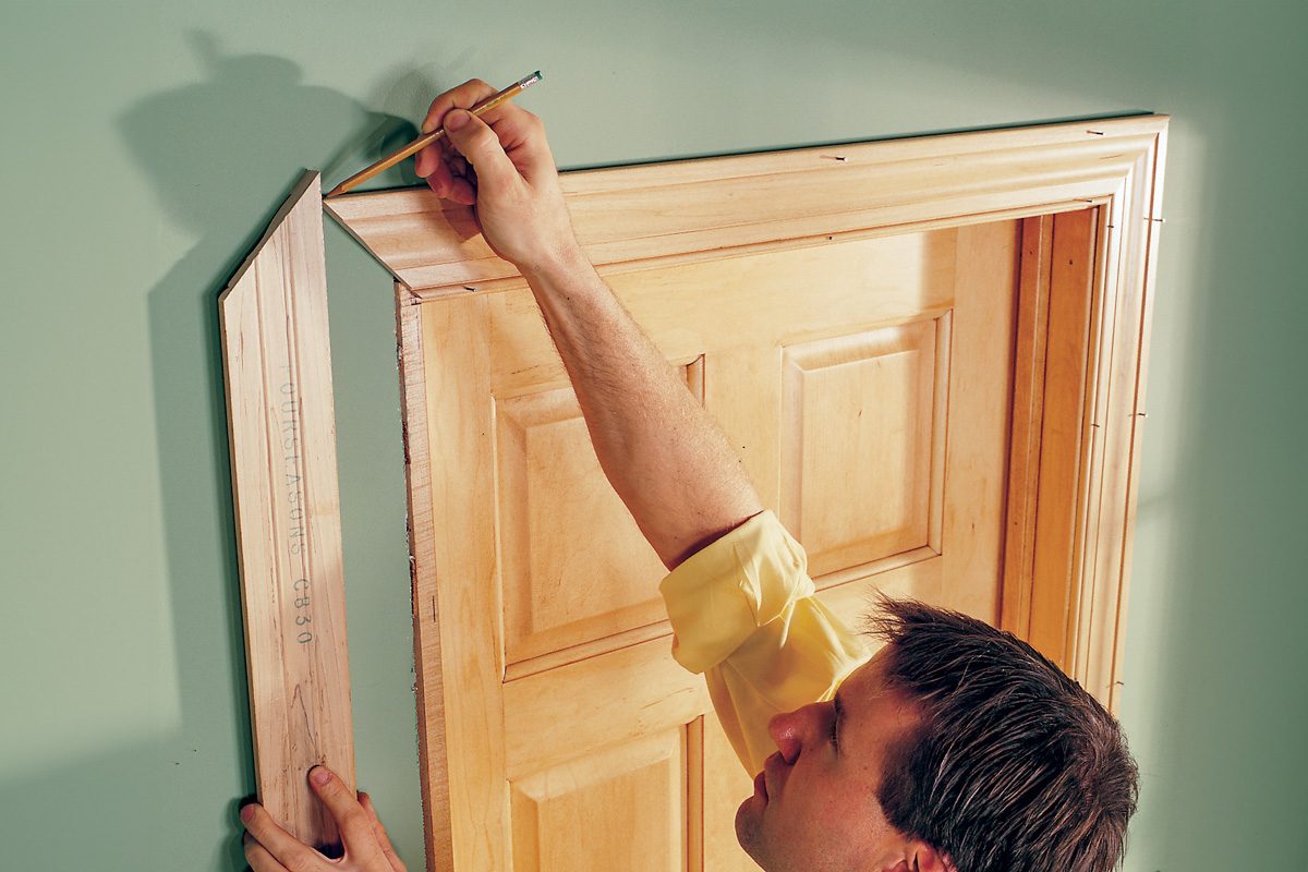 man holding trim in place and marking it