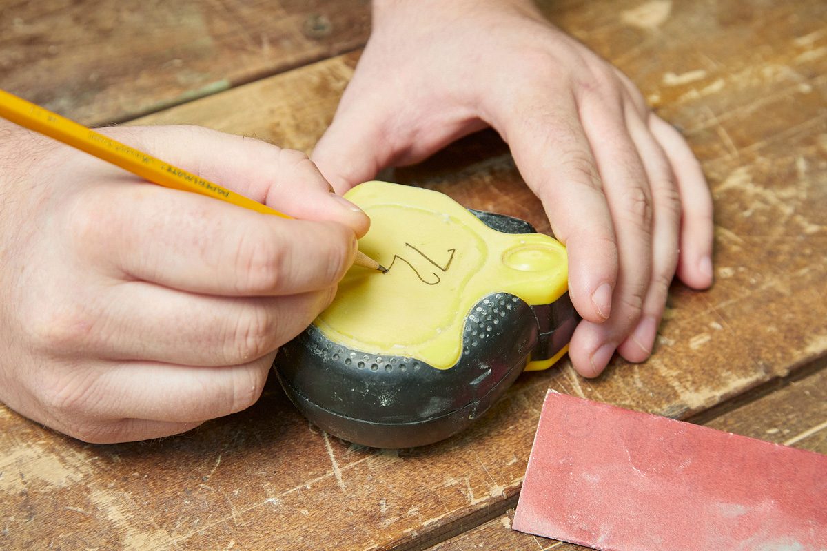 person jotting down number on masking tape stuck to tape measure