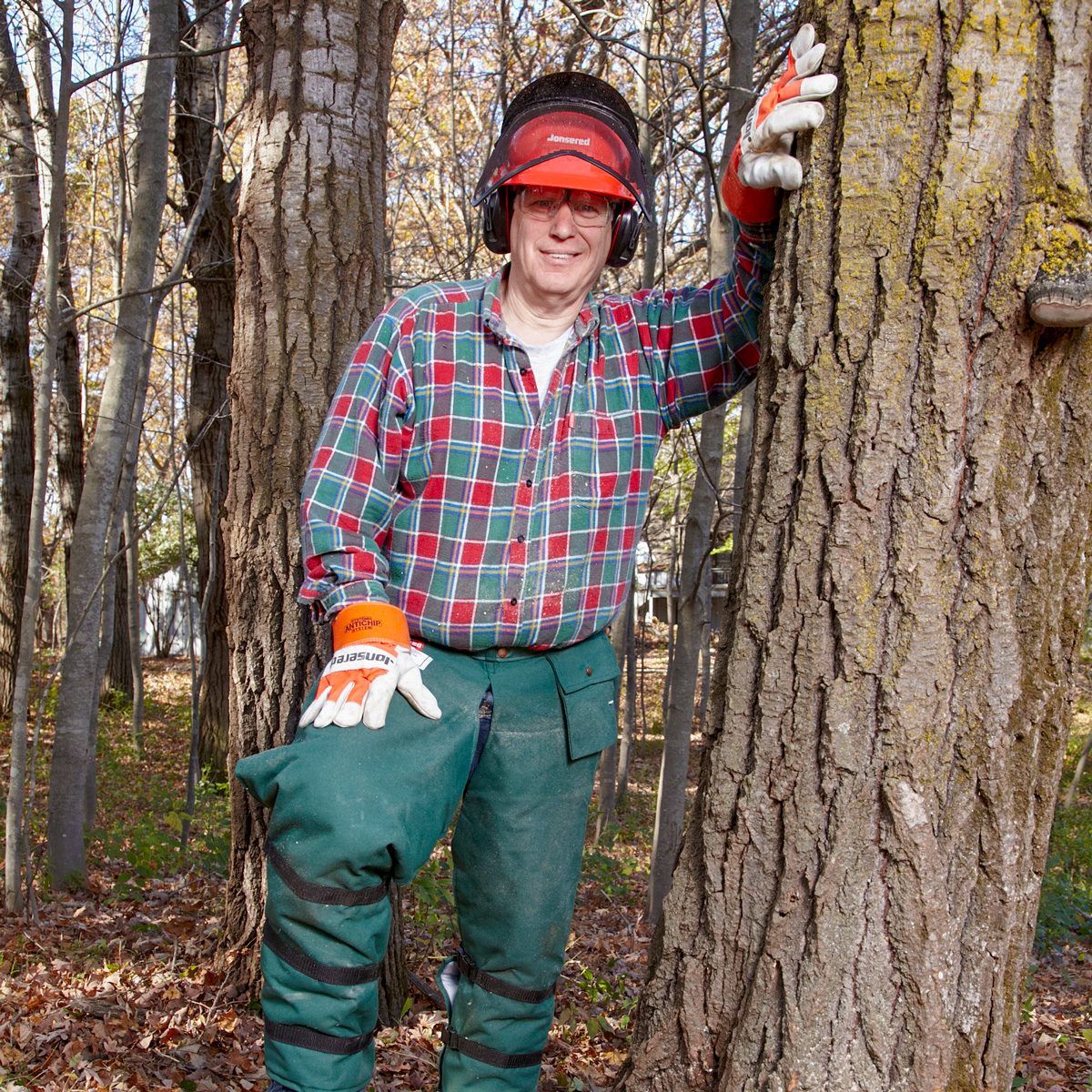 man in safety gear posing next to tree