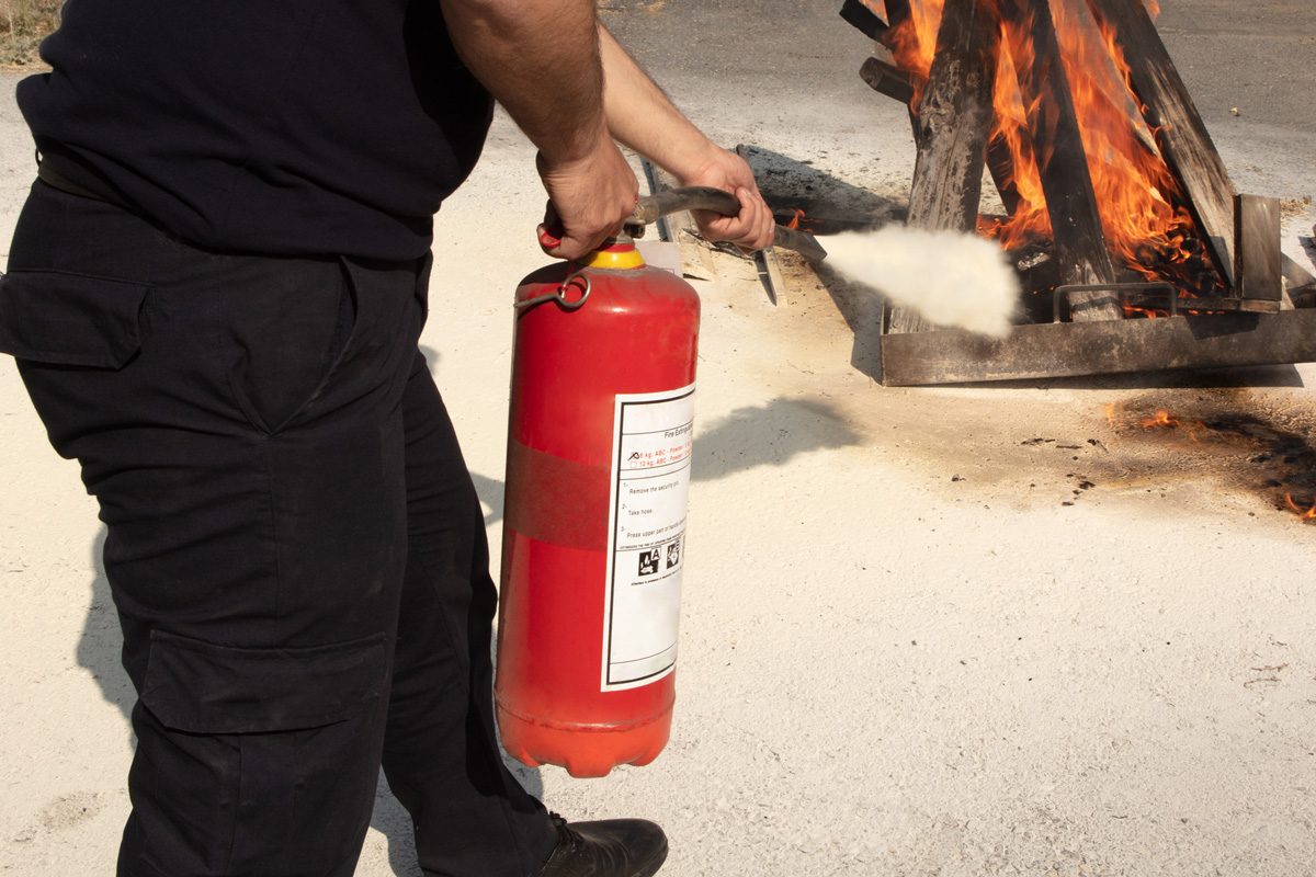 man using fire extinguisher on fire