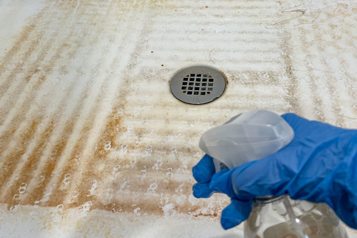 spraying mouldy surface with cleaner spray