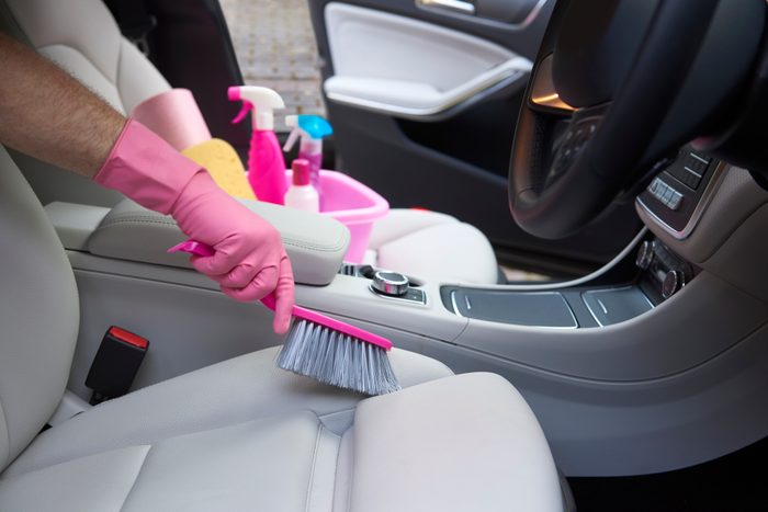 Person scrubbing car seat with a pink brush