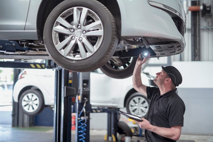 Engineer checking car on ramp in car service centre