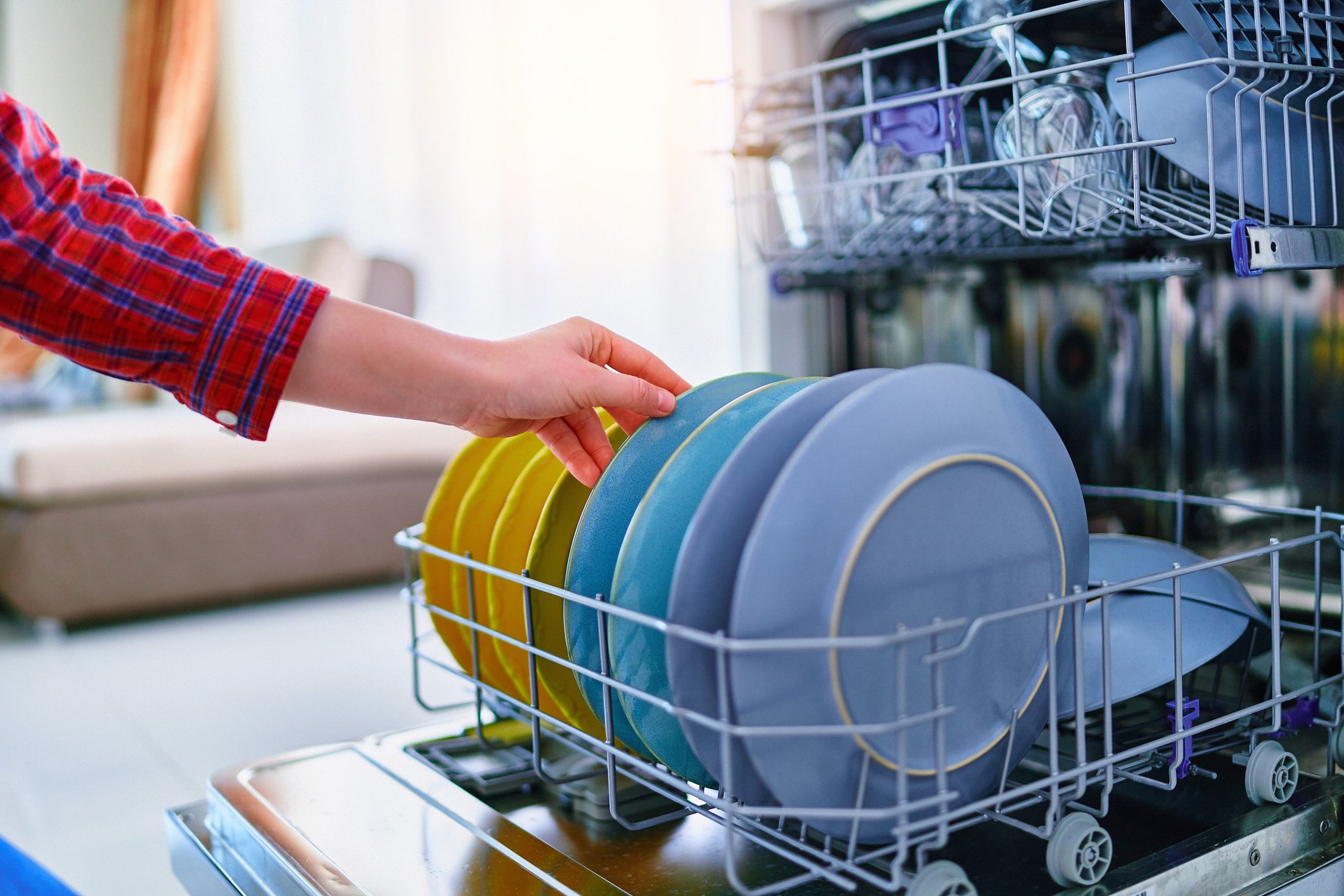 Person touching a row of colorful stacked plates in a dishwasher