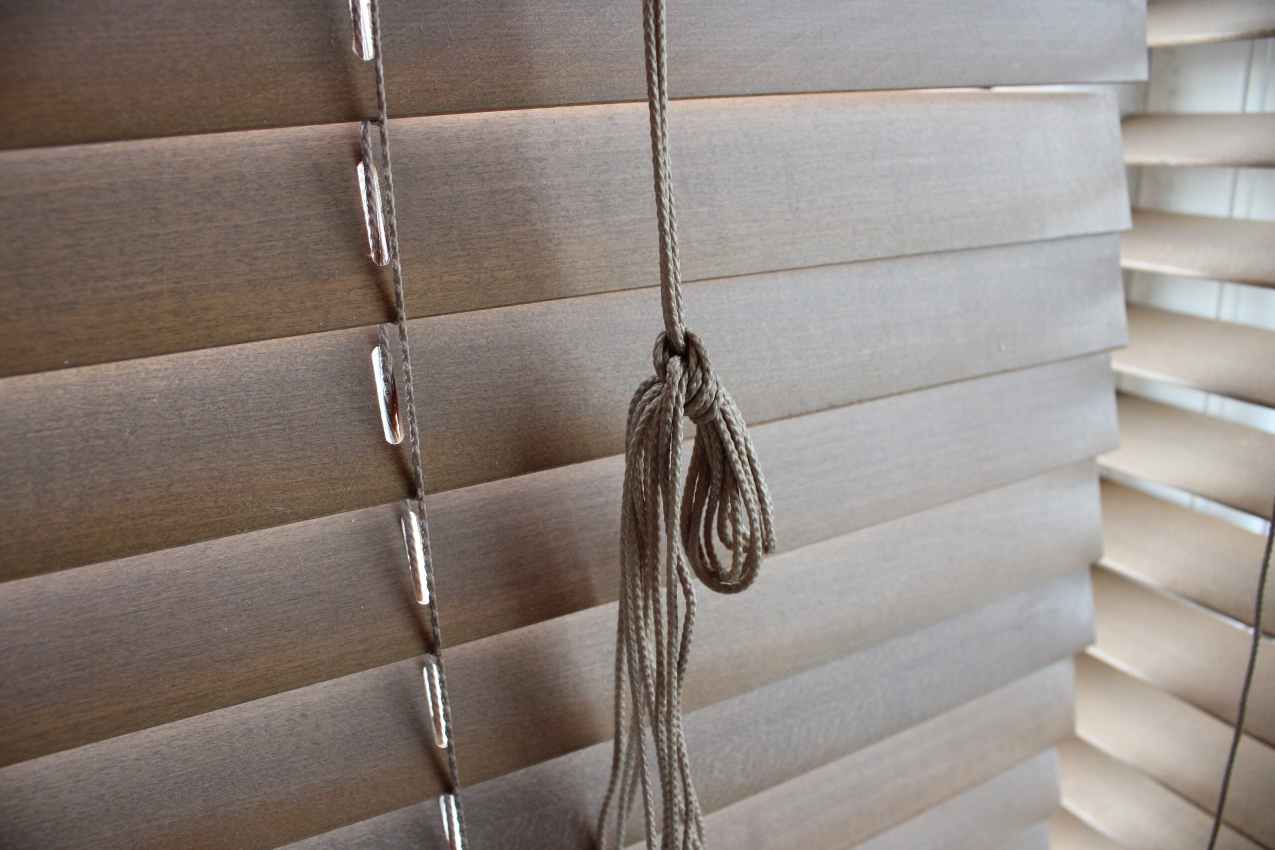 Close up picture of wooden modern blinds with tied blind rope
