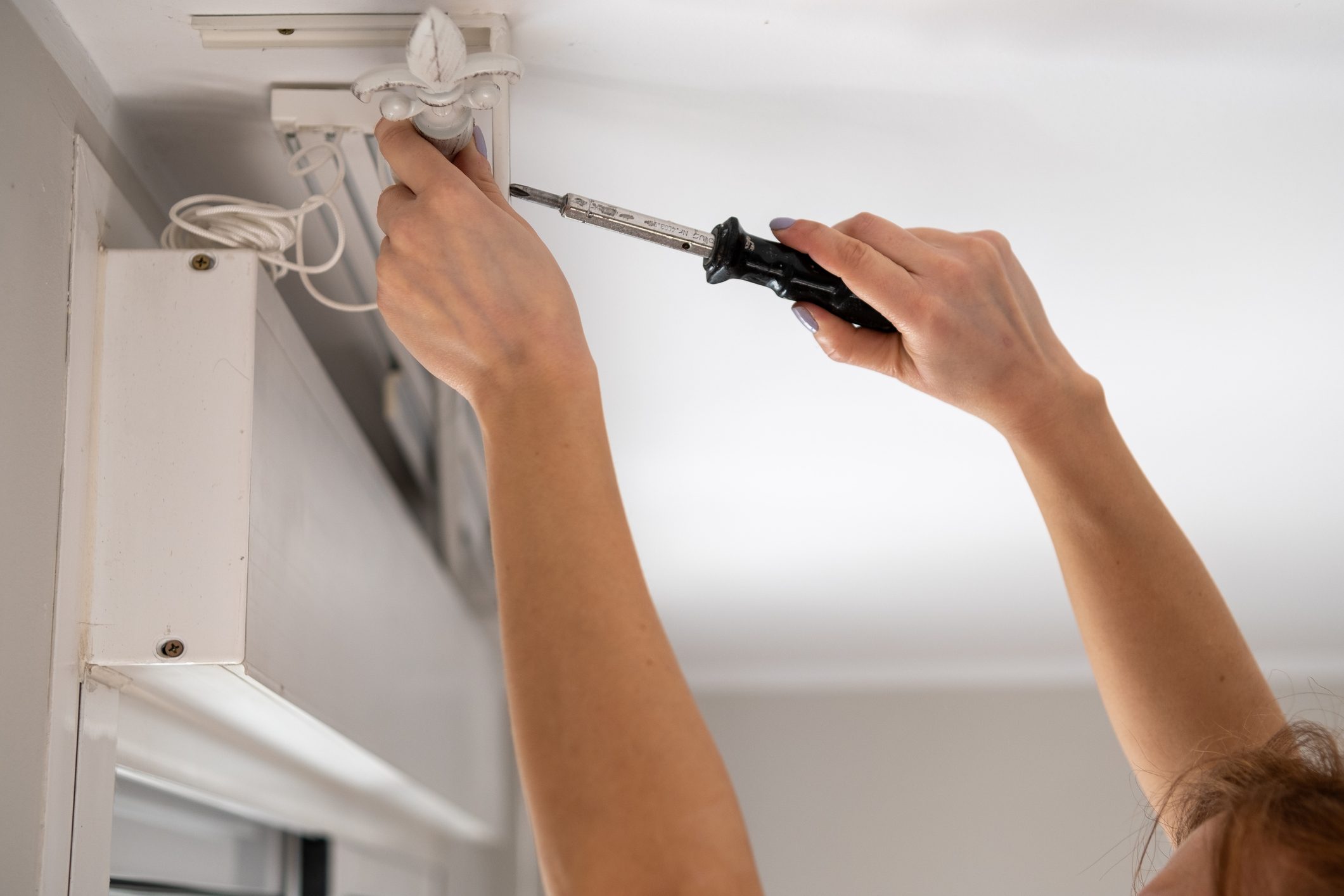 Handywoman replacing roller blind using screwdriver at home