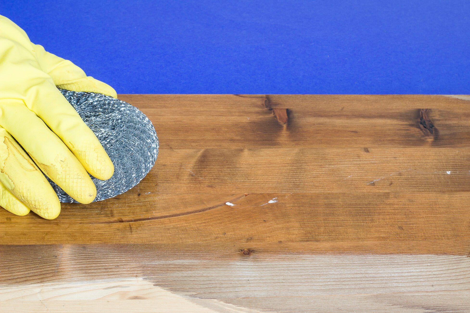 Woman's hand treating plank with steel wool and vinegar