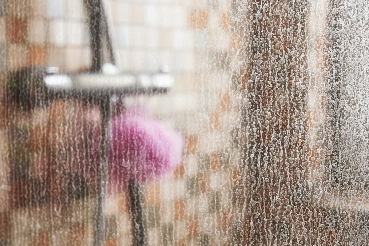 glass of shower cabin covered in limescale