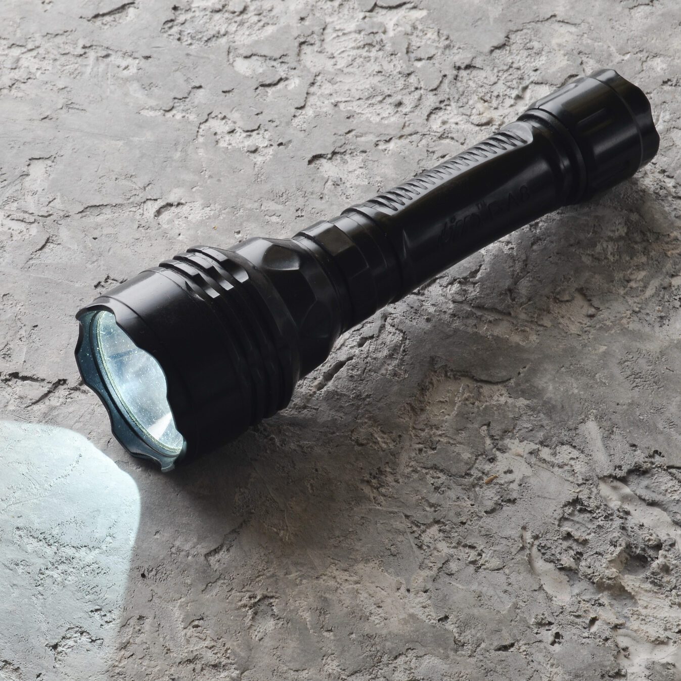 A glowing flashlight on a gray concrete table.