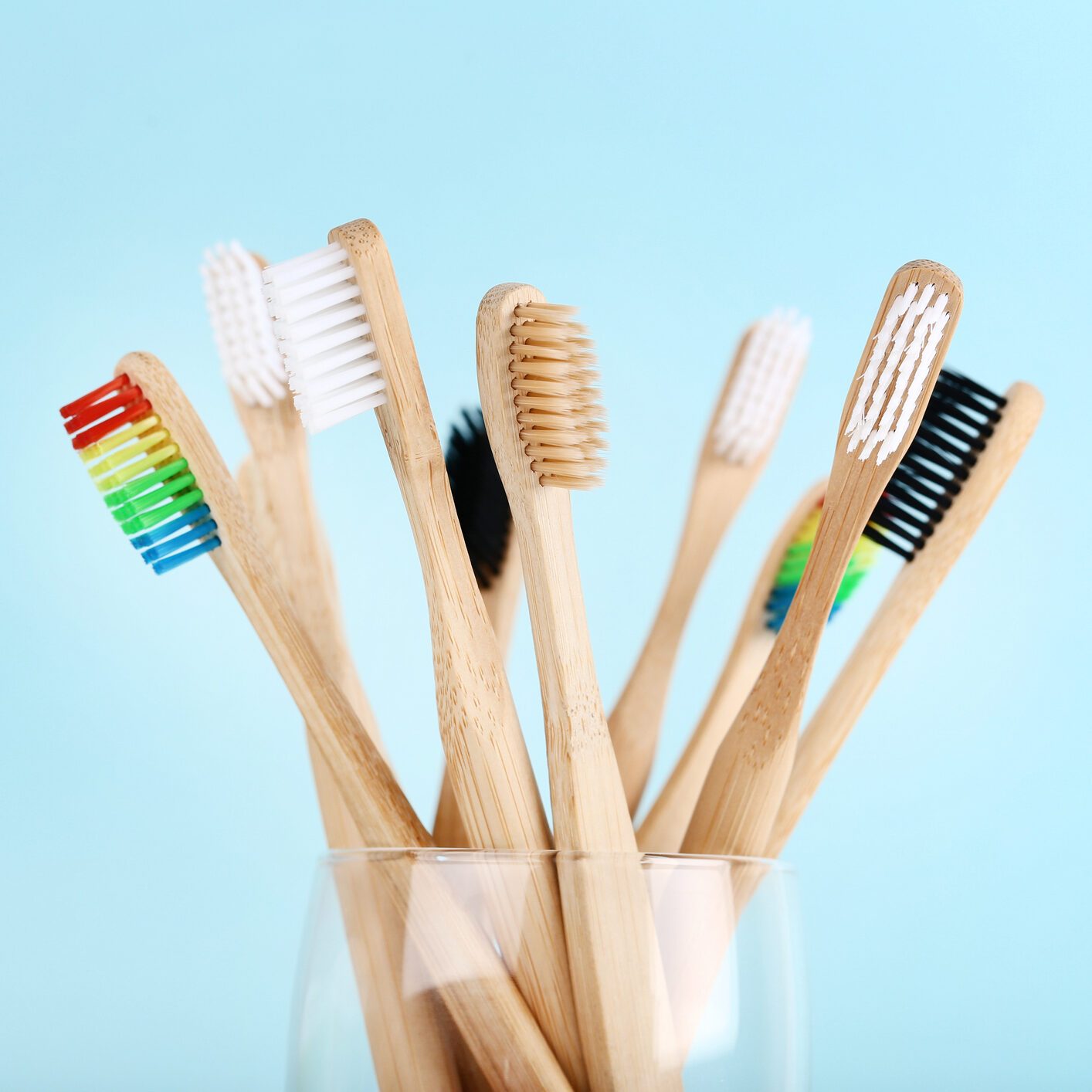 Bamboo toothbrushes in glass on blue background