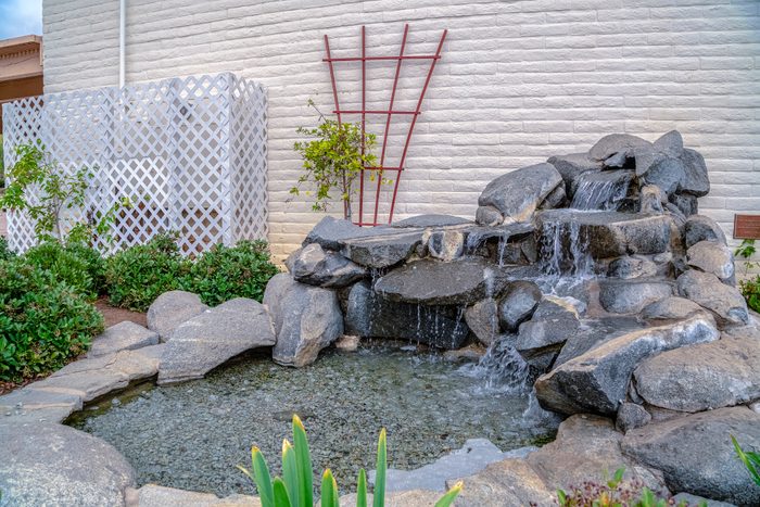 Artificial stone cascade waterfall in backyard on a sunny day