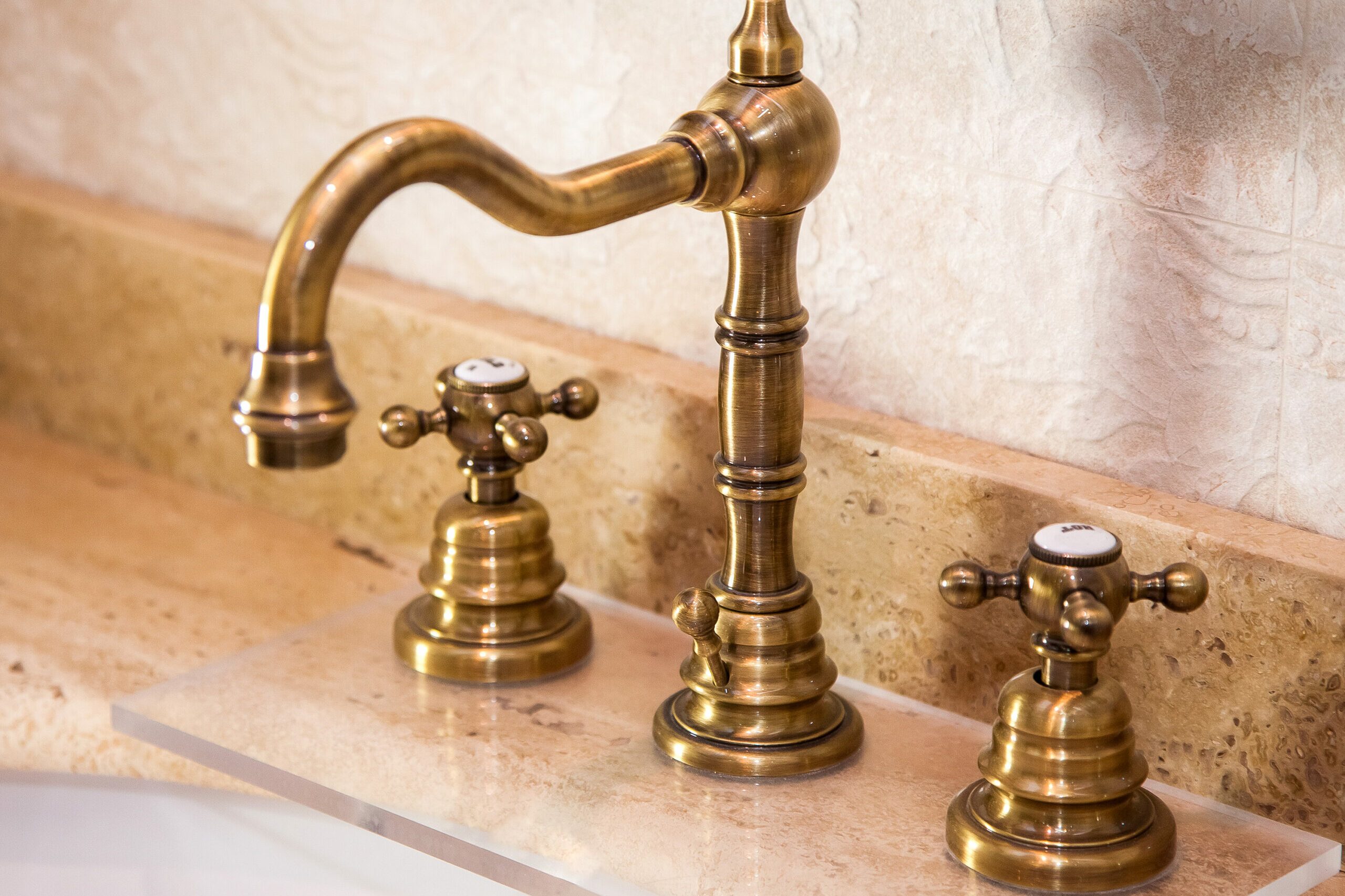 vintage faucet with copper valve taps on a marble stone washbasin, close up.