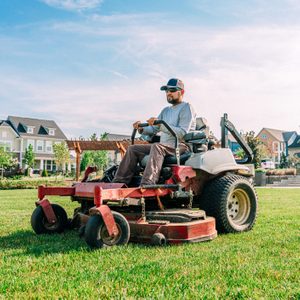 Man driving a lawn mower on a residential patch of grass