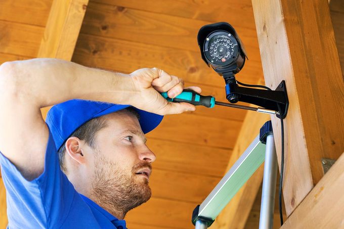 Technician installing surveillance camera in the house carport
