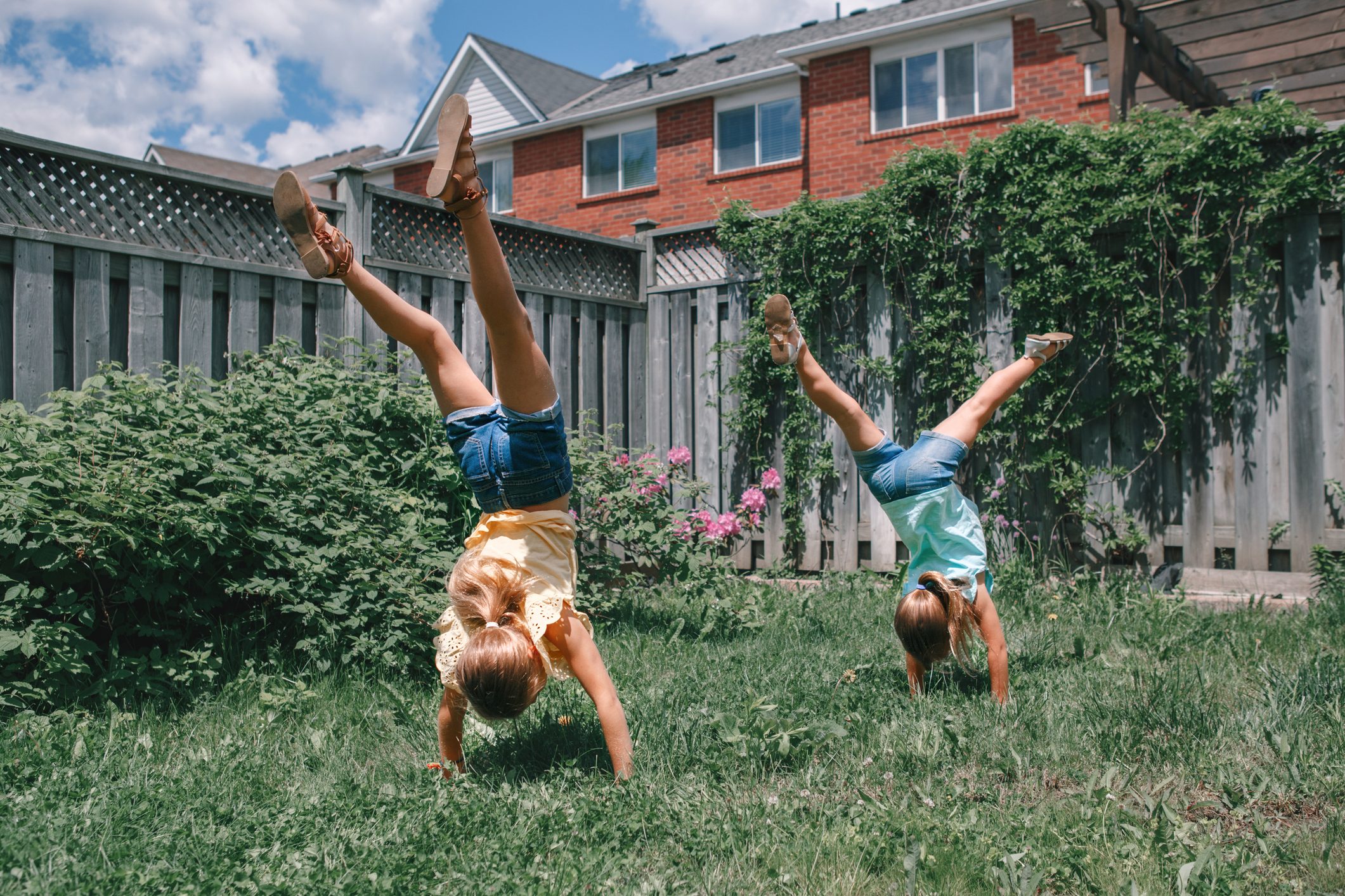 Girls cartwheeling on a lush lawn