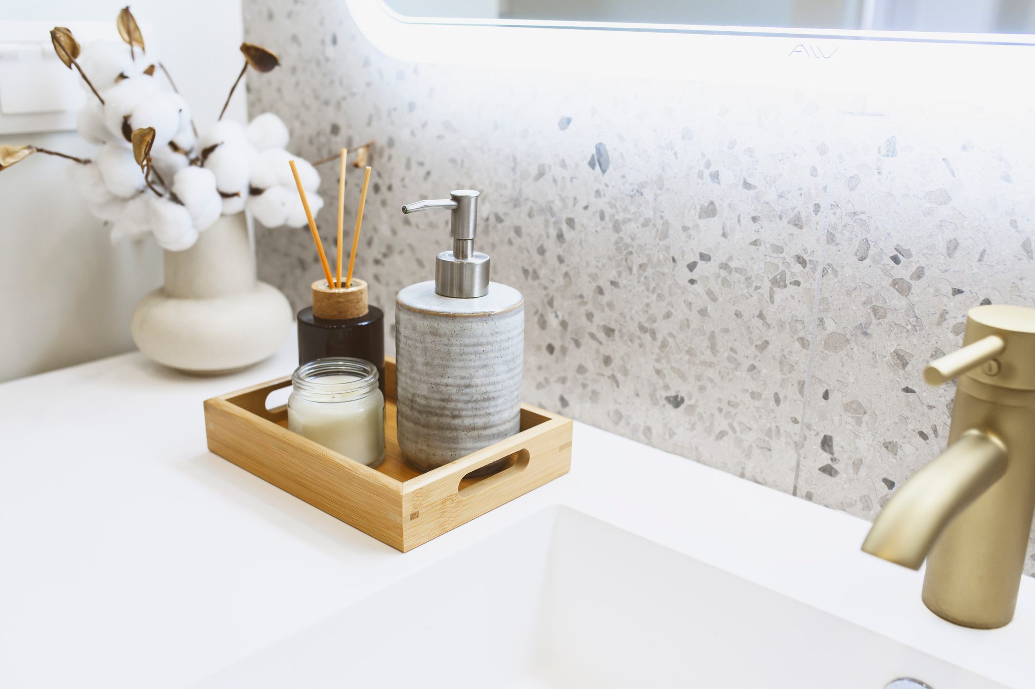 Modern luxury bathroom details. Hand soap dispenser, candle, towels in white and grey tones. Scandinavian minimalistic interior style.