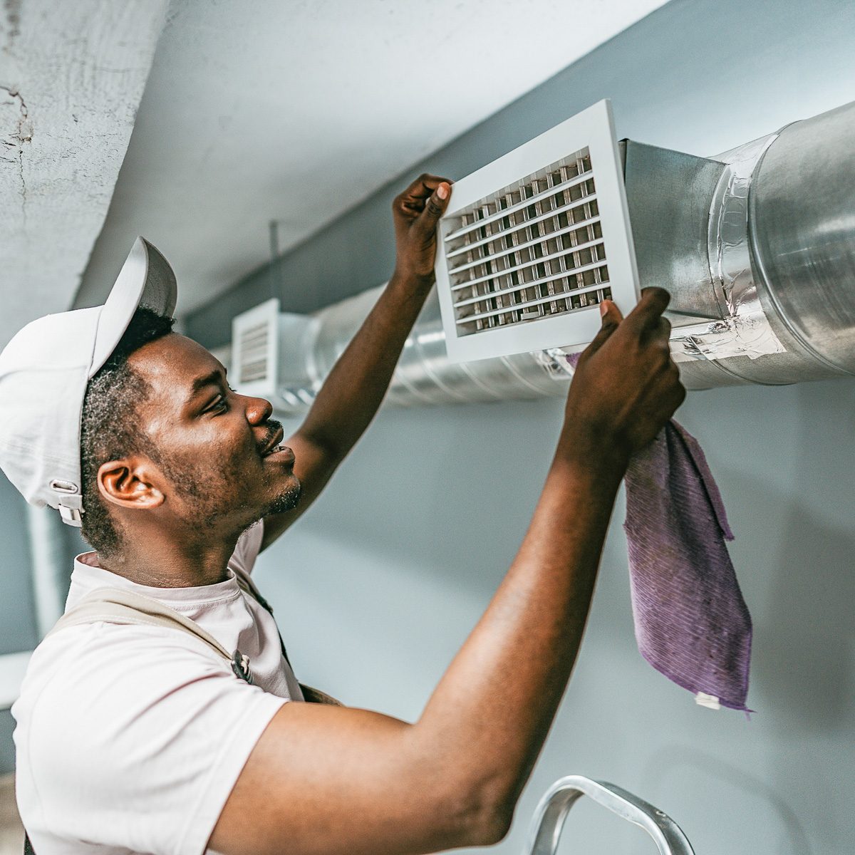worker adjusting air vent in basement