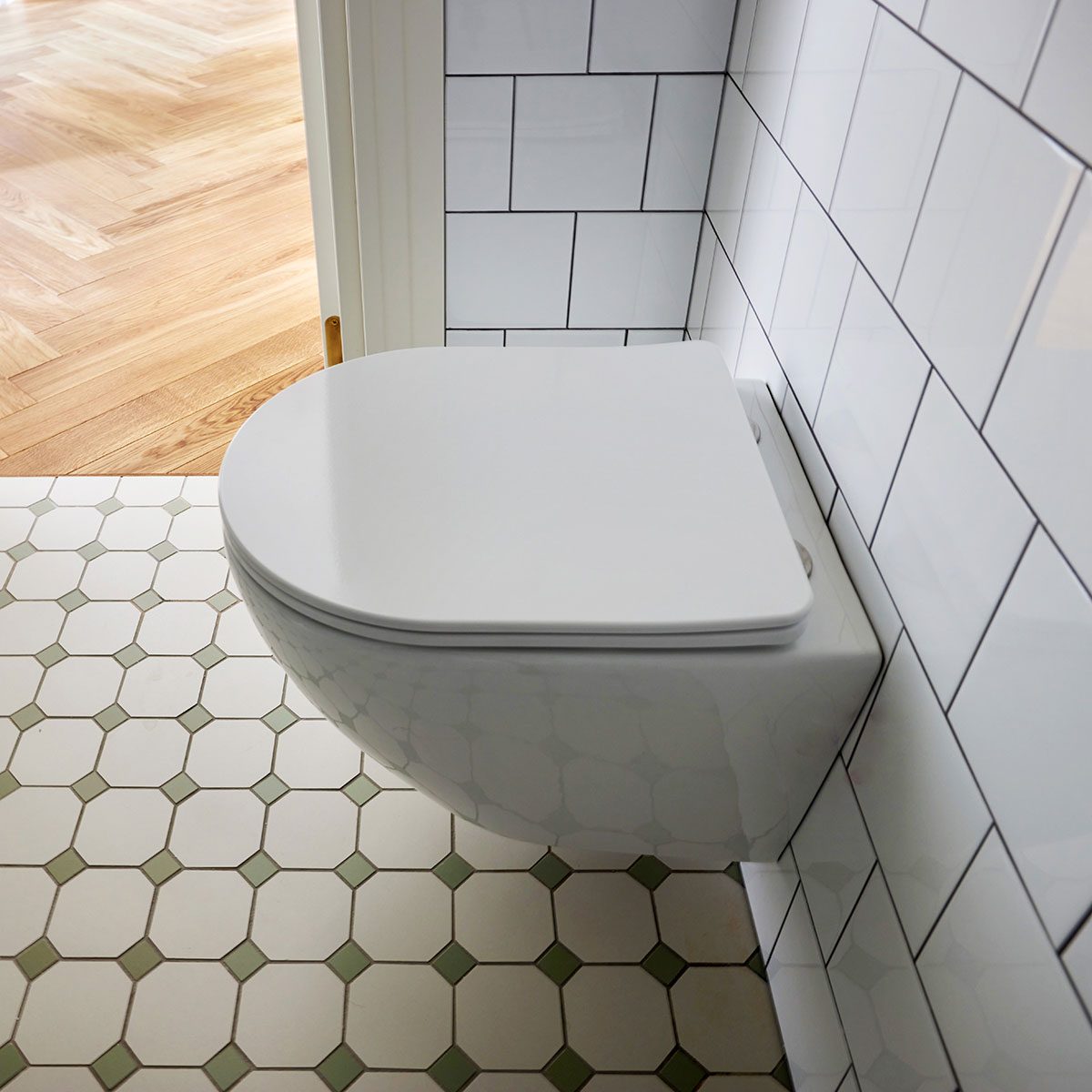 modern minimalist bathroom features a wall mounted toilet and chic tile flooring, creating a stylish look