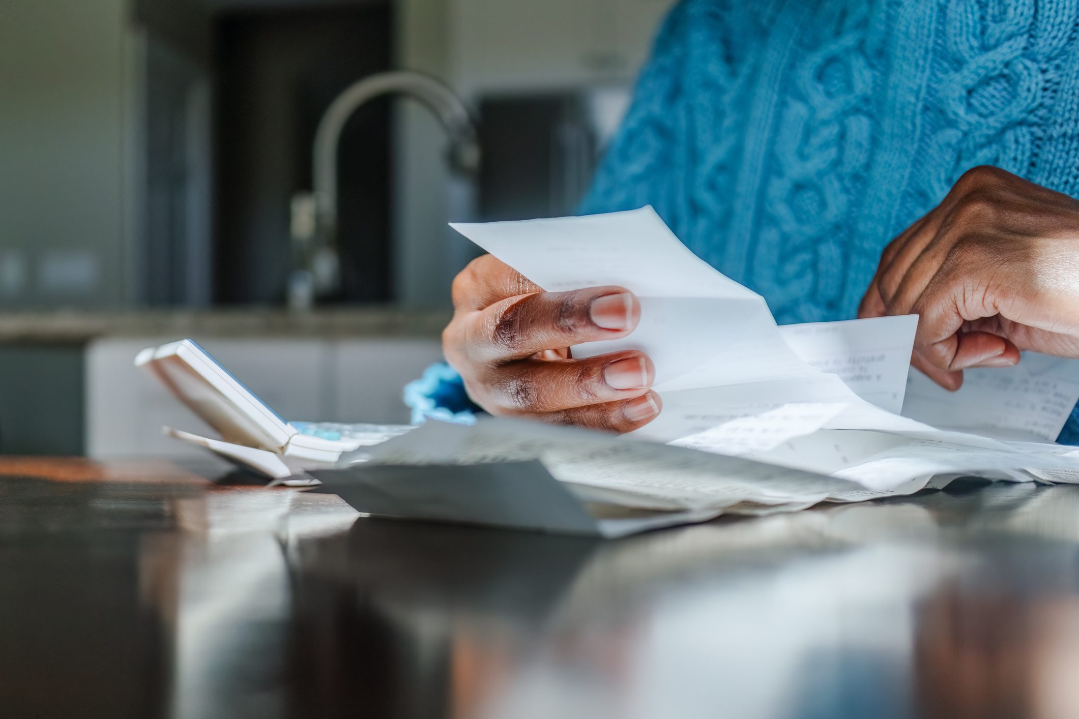 Woman Reviews Receipts at Kitchen Table