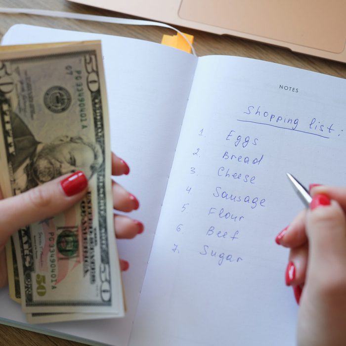 Woman makes shopping list and holds money