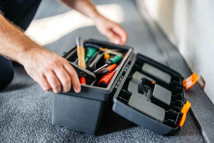 Electrician Opening A Tool Box In An Empty Apartment Under Renovation