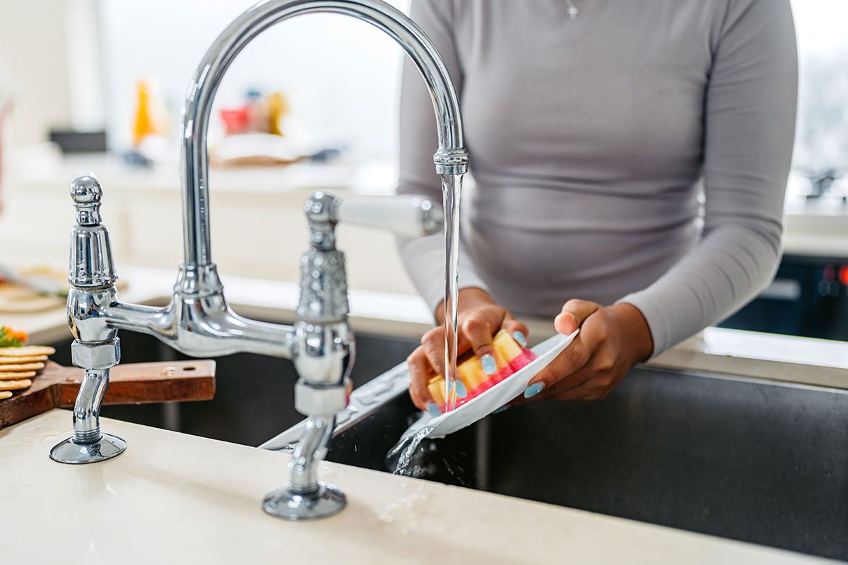 Young Girl Washing Dishes In The Kitchen