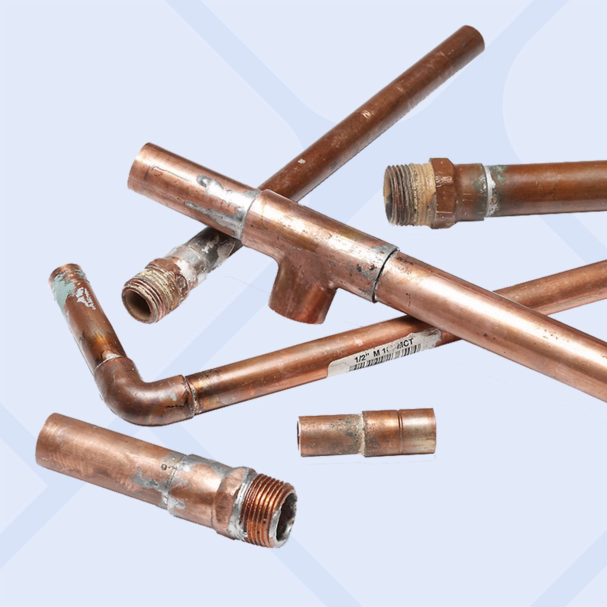 Several copper pipes with threaded and soldered ends, some bent at angles, are arranged on a light surface. The pipes show signs of use and oxidation.