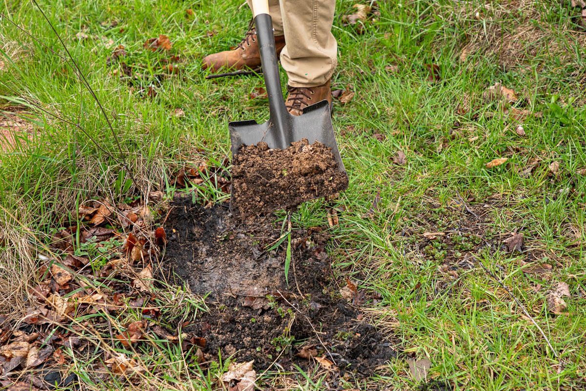 person digging into ground with shovel