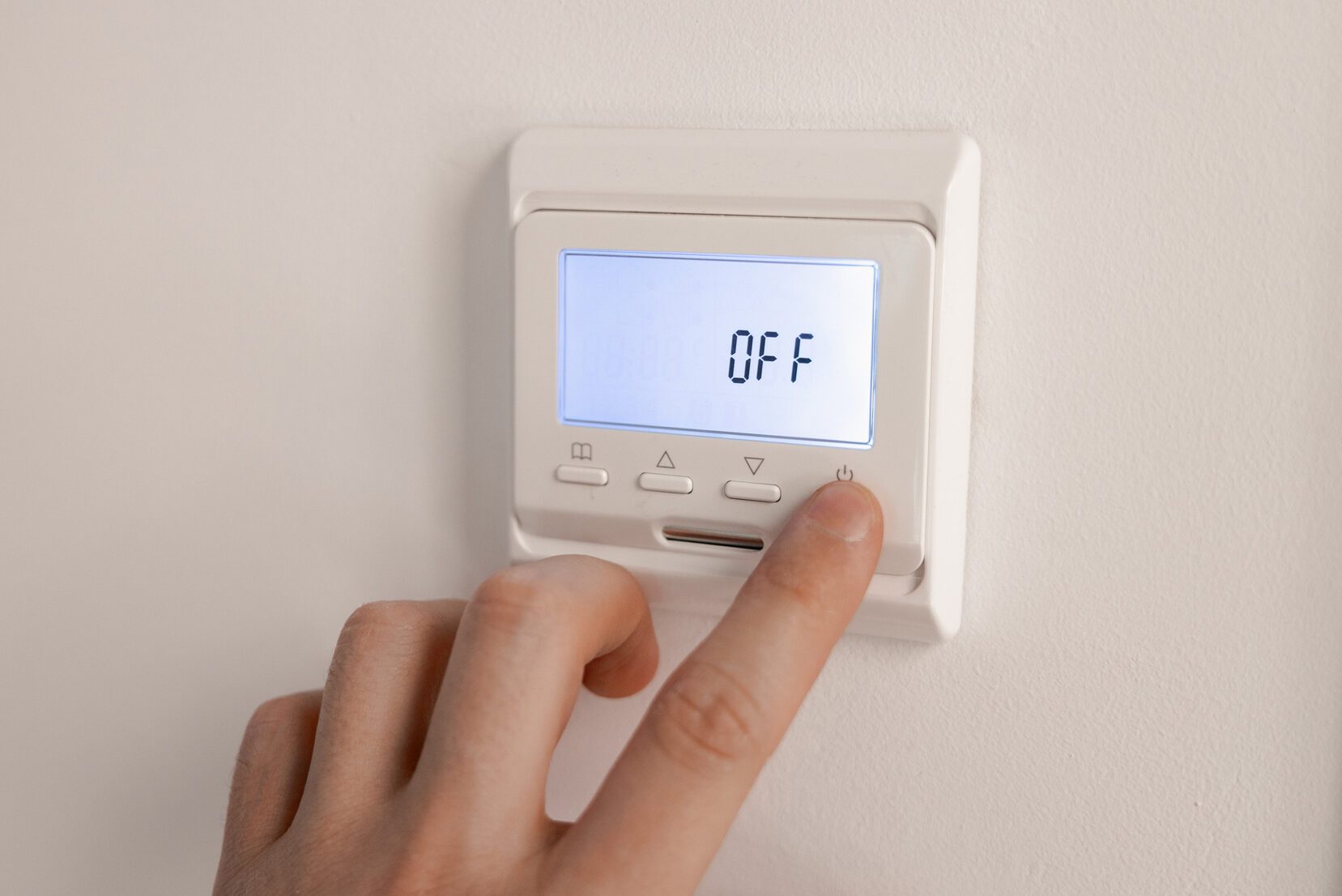 White thermostat for heating the warm electric floor and the boiler on the wall. the person turned off the finger control. information on the electronic display with backlight Off. ost saving