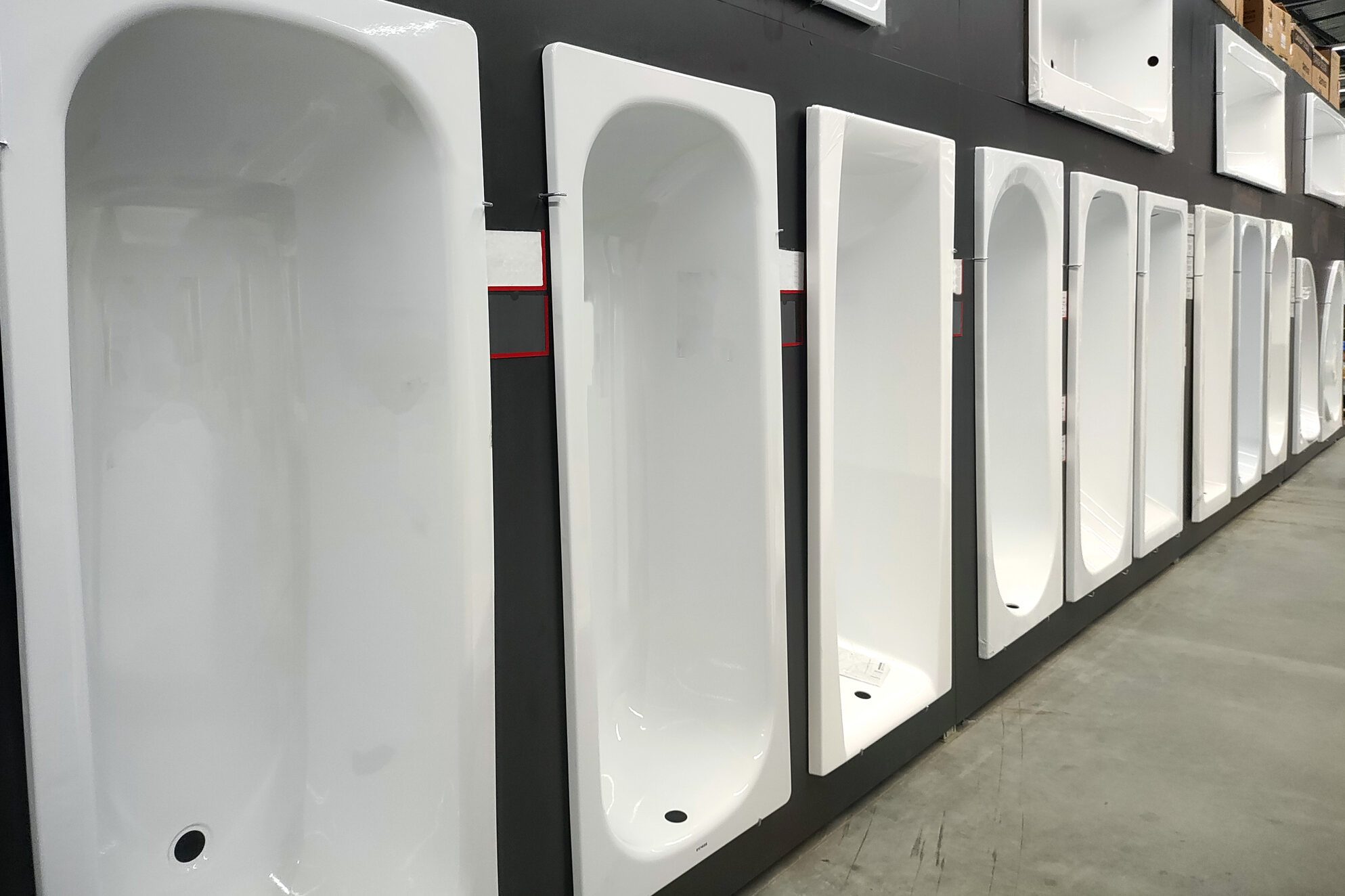 Sale of cast iron and acrylic bathtubs in a plumbing store, background