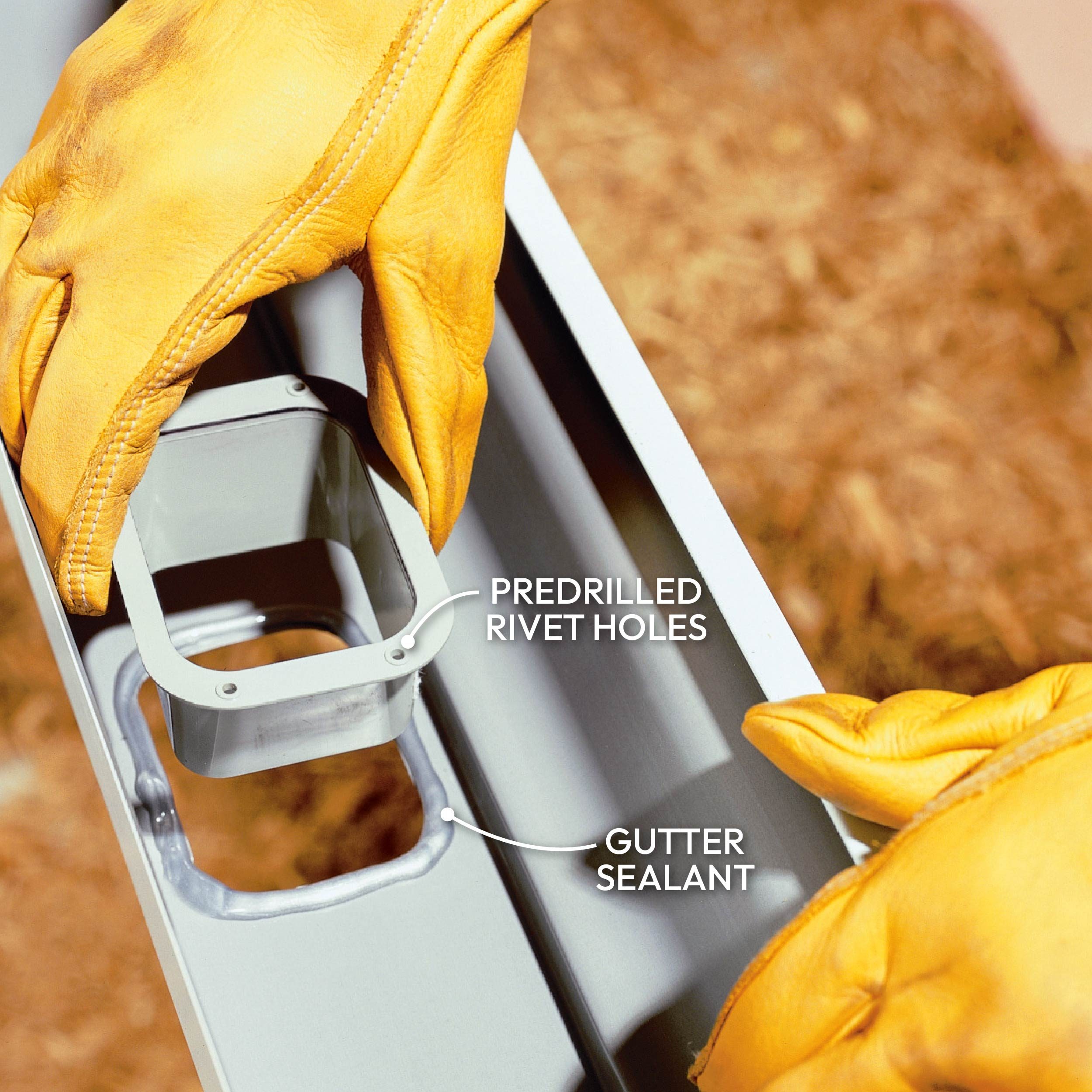 A hand in a yellow glove holds a gutter component, showing rivet holes and sealant, against a textured, earthy background.