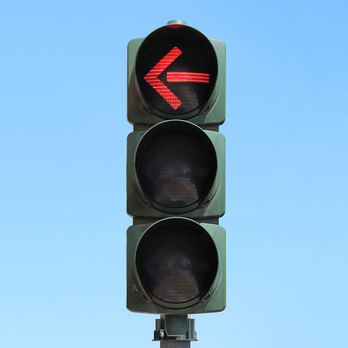 Traffic light isolated in the sky with Red arrow light on.