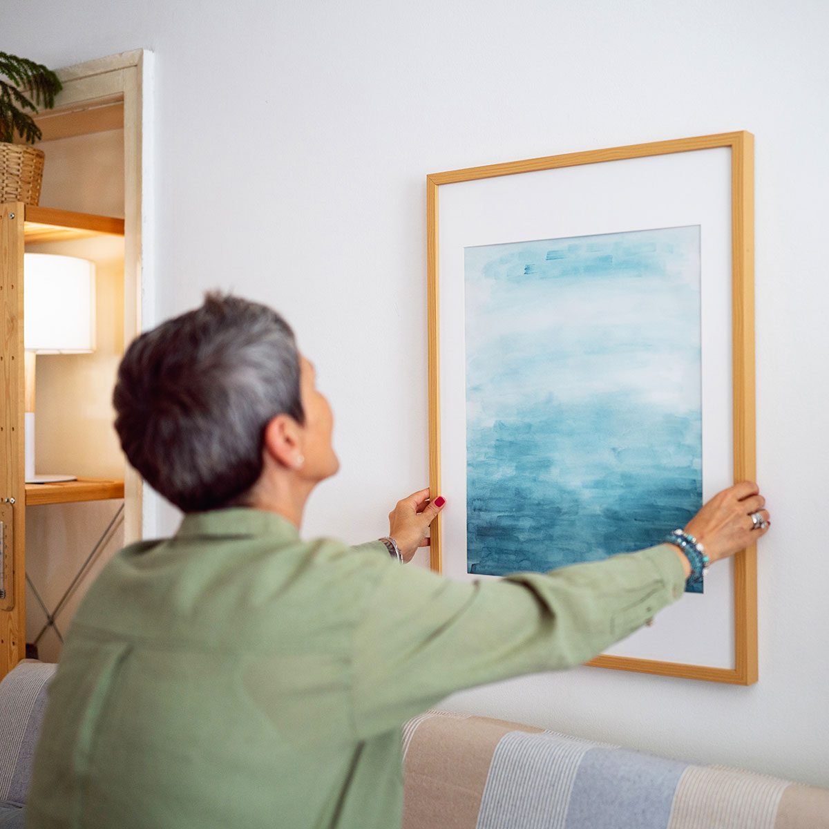 Woman decorating her home with a new painting