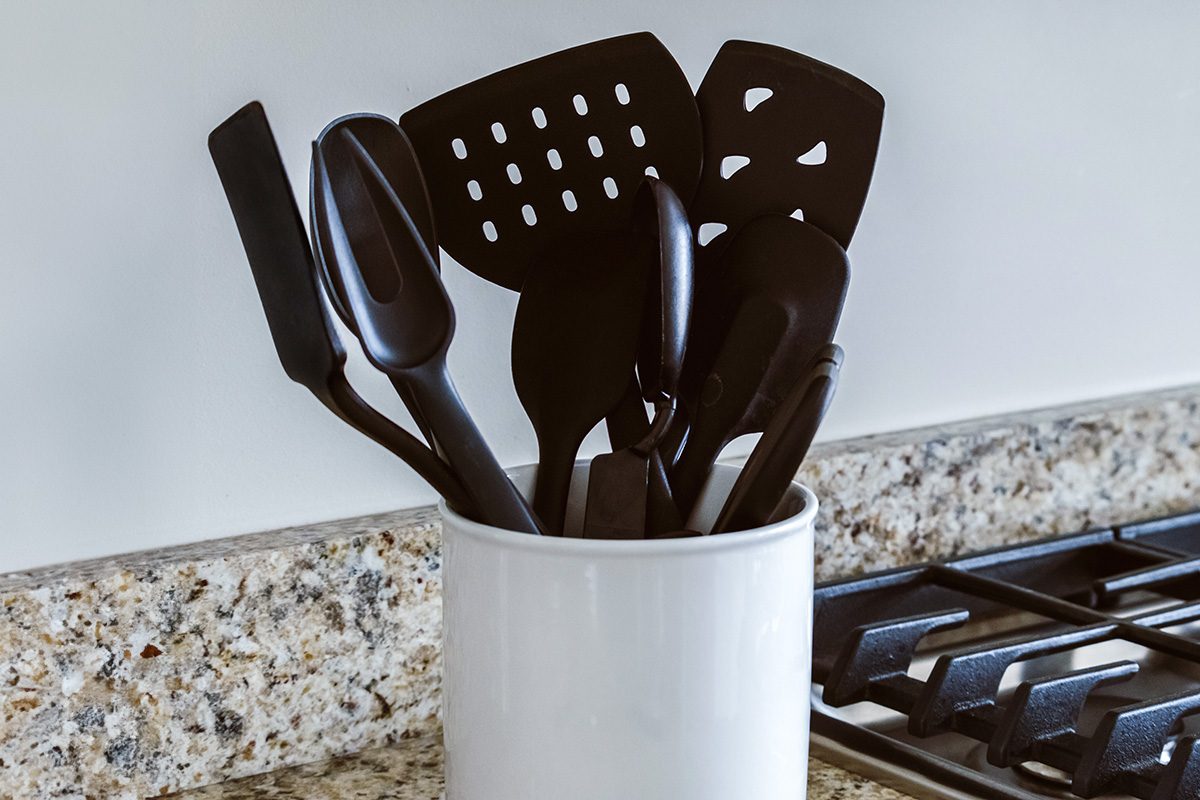 Close-up view of black plastic cooking utensils in container on kitchen counter