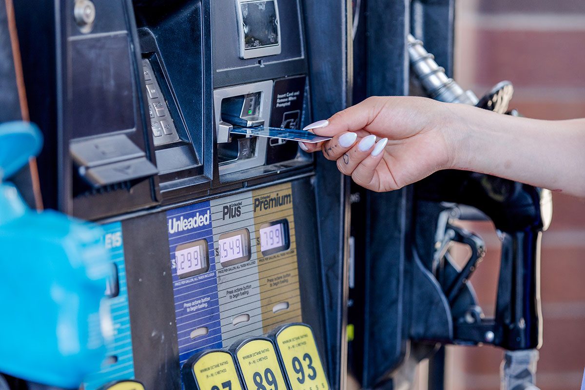 Woman using credit card at gas pump, paying for fuel