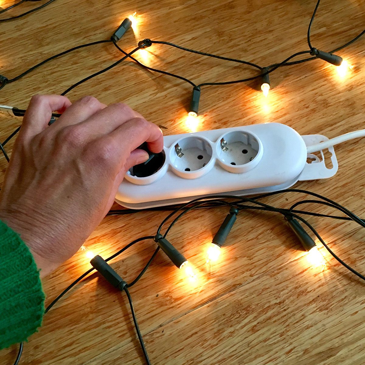 First person perspective of woman testing Christmas lights.