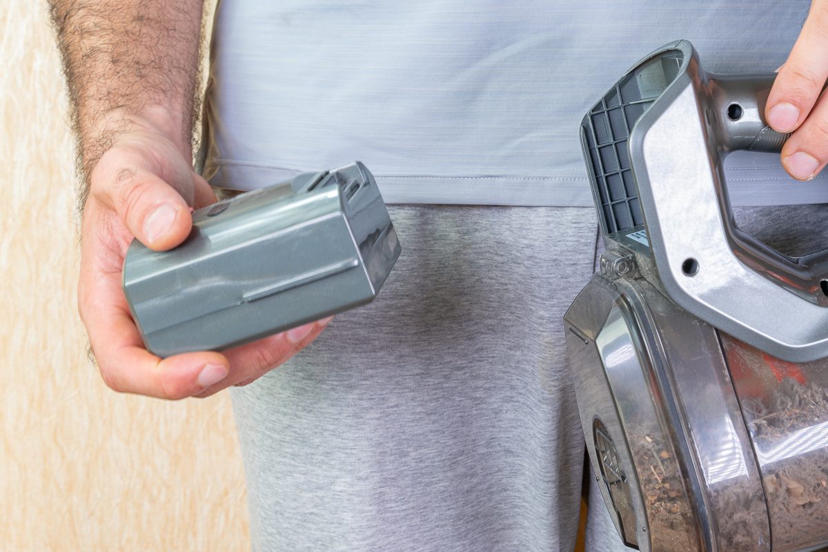 close up of man removing batteries from vacuum cleaner