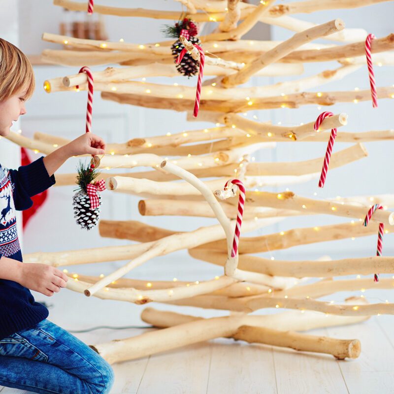 child decorating wooden Christmas tree