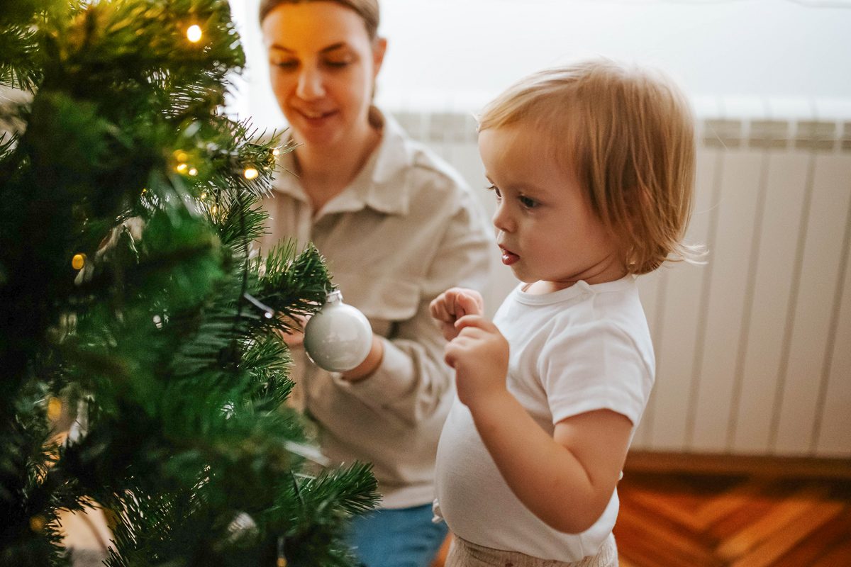 little girl decorating christmas tree with her mother