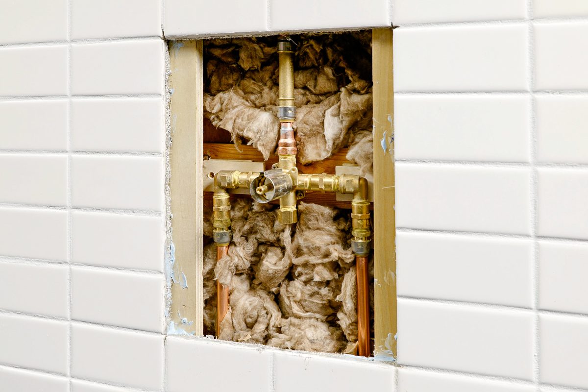 exposed plumbing for shower valve behind removed tiles and cement board