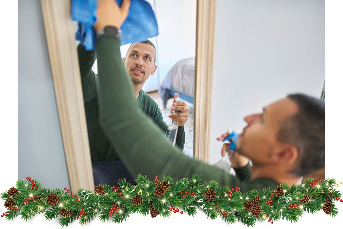 Man cleaning a mirror at home 