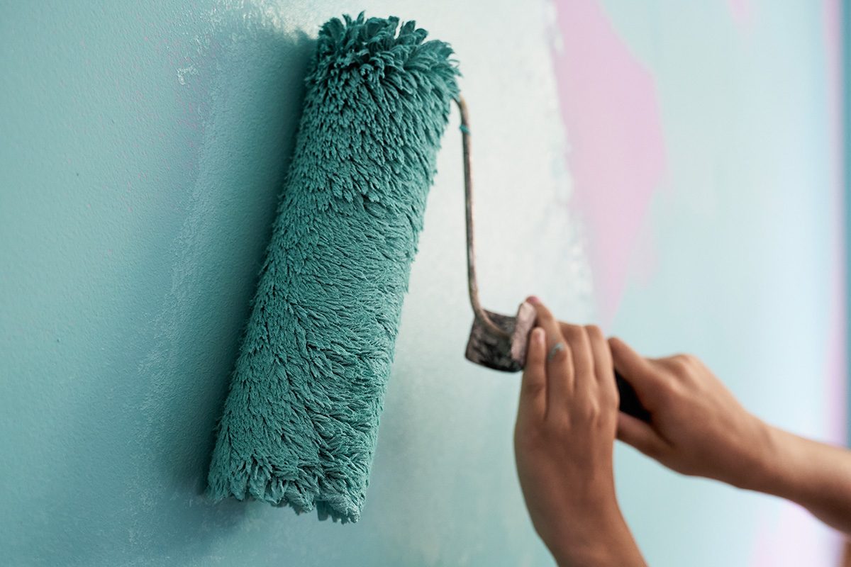 Caucasian painter hands painting a wall of a room. 
