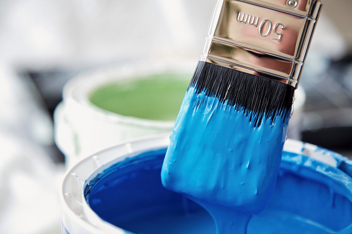Close up of blue paint pot and dripping paintbrush