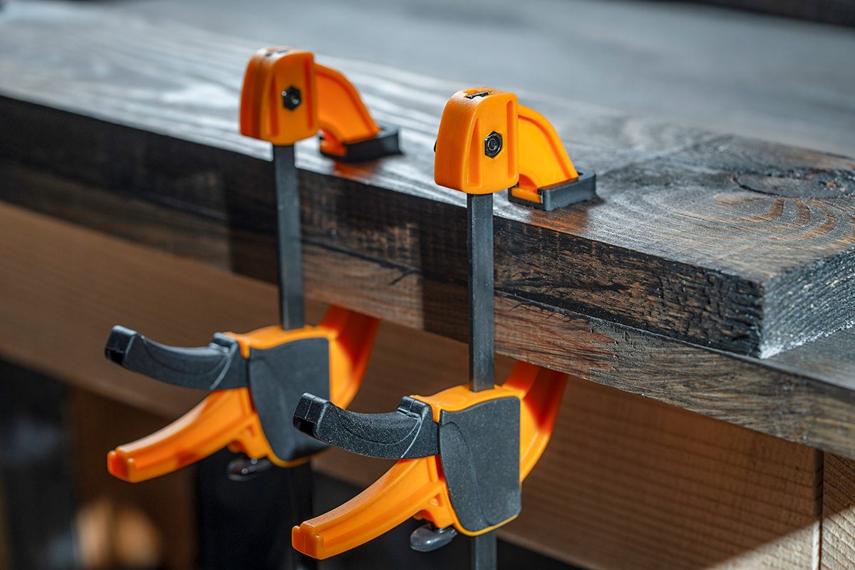 Carpenter two clamps are fixed to boards, closeup. Carpentry tools in the home workshop 
